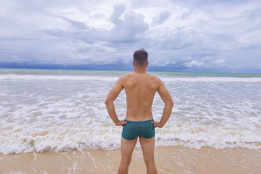 Retrato de um jovem de pé ao ar livre olhando para o mar