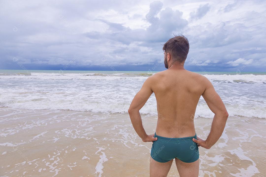 Retrato de um jovem de pé ao ar livre olhando para o mar