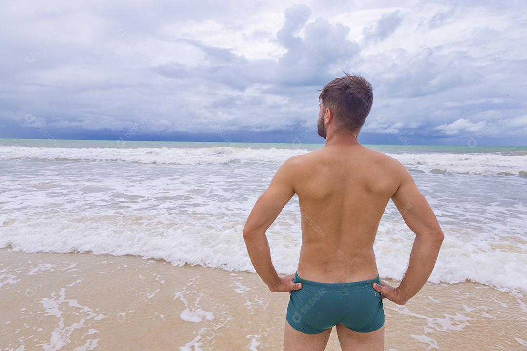 Retrato de um jovem de pé ao ar livre olhando para o mar