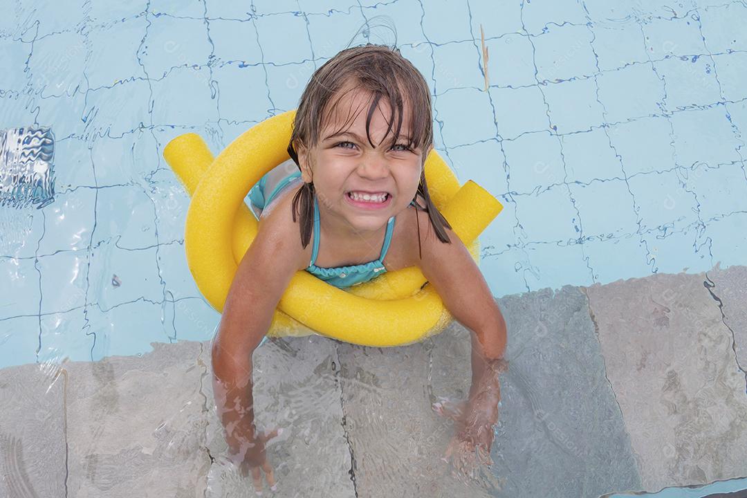 Garota feliz jogando na piscina no hotel de férias