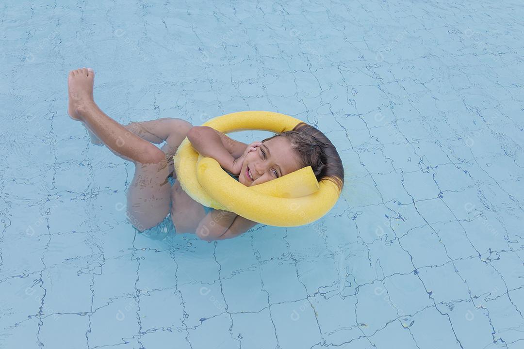 Garota feliz jogando na piscina no hotel de férias