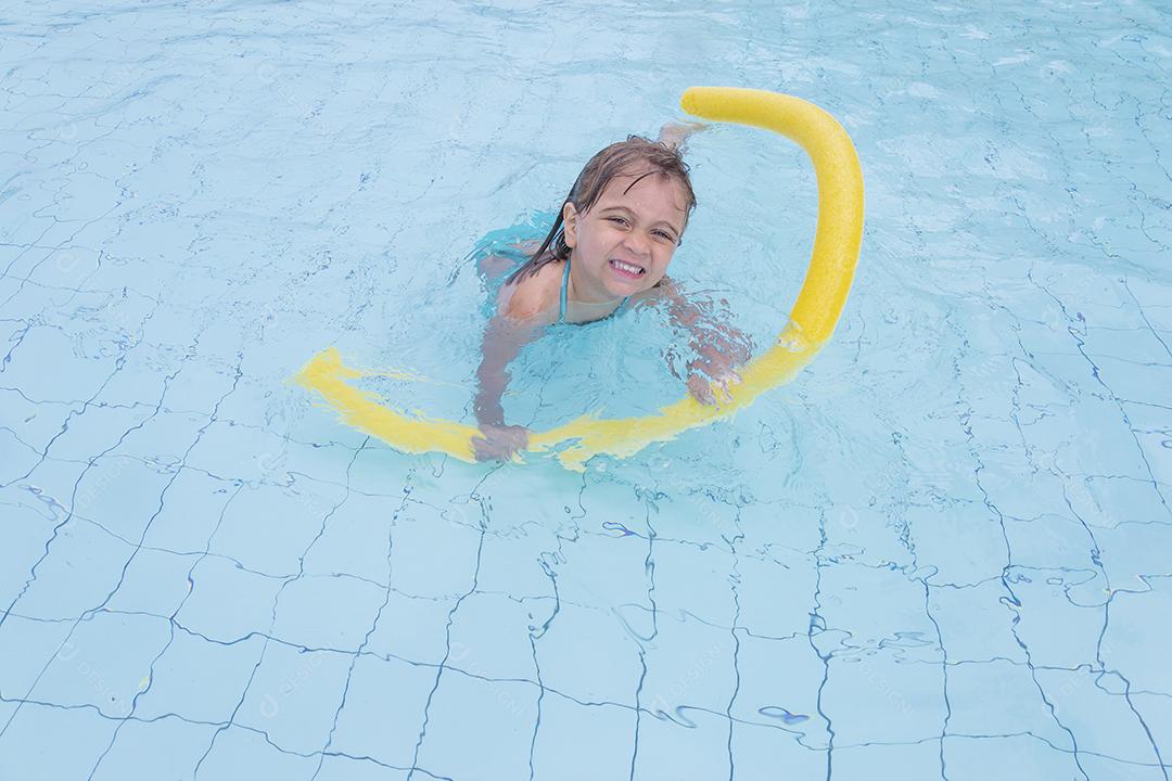 Garota feliz jogando na piscina no hotel de férias