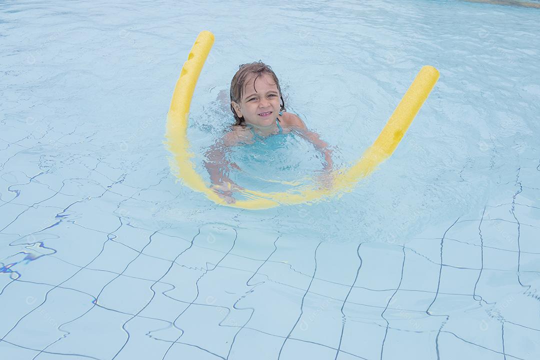 Garota feliz jogando na piscina no hotel de férias