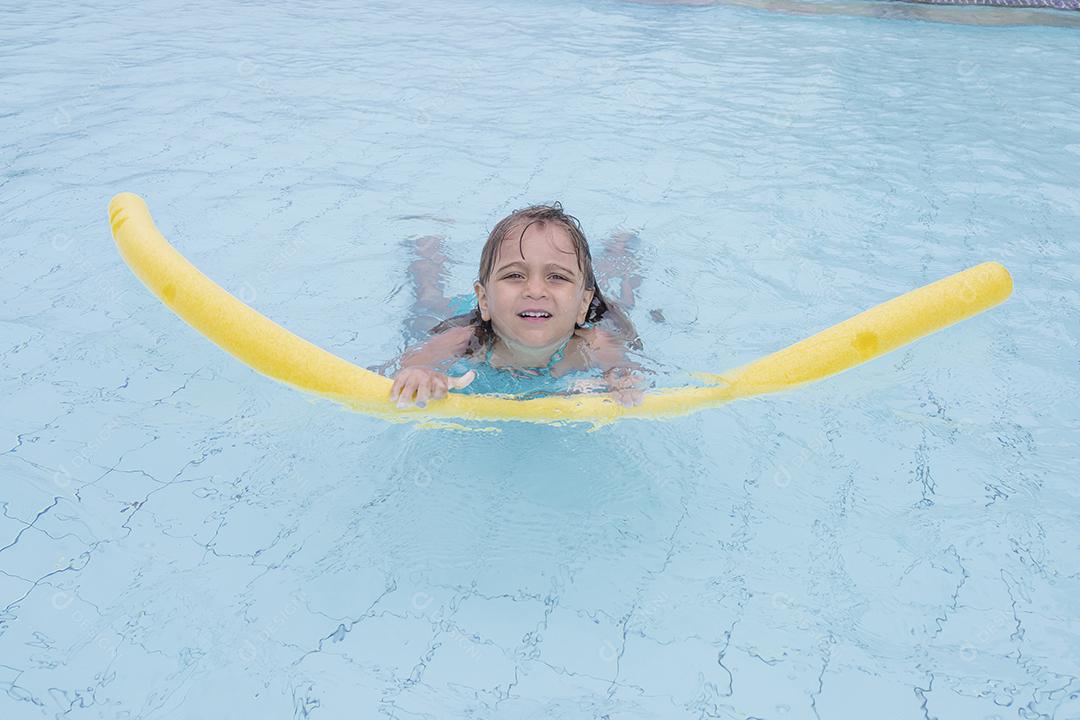 Garota feliz jogando na piscina no hotel de férias