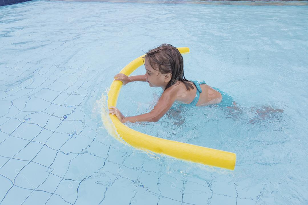 Garota feliz jogando na piscina no hotel de férias