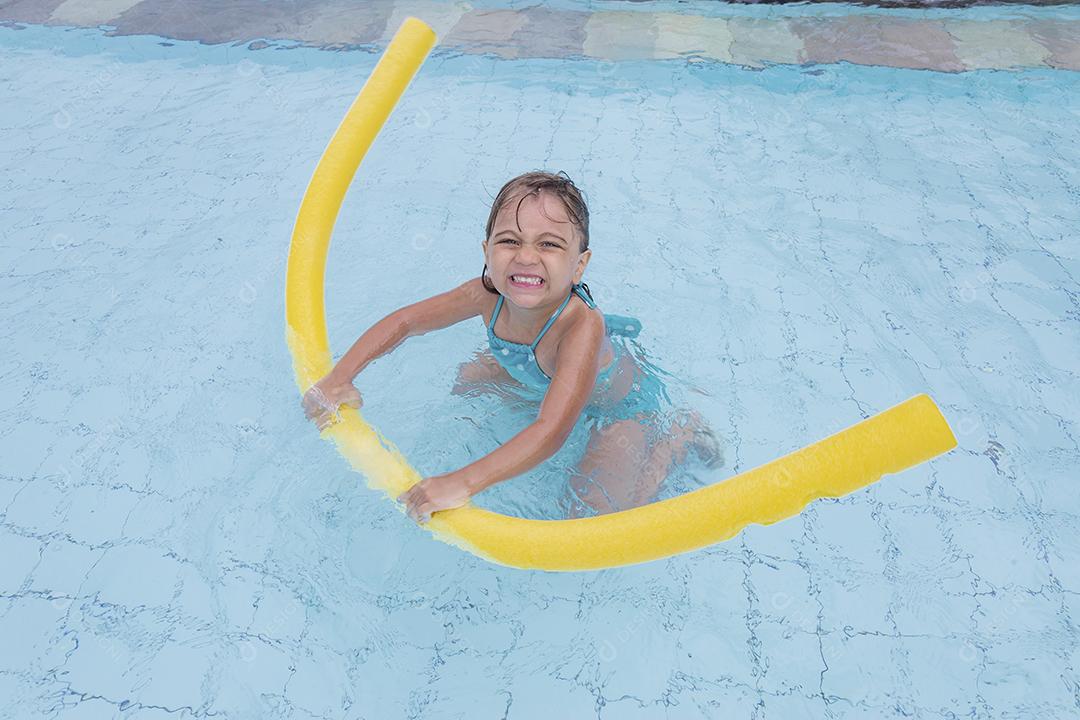 Garota feliz jogando na piscina no hotel de férias