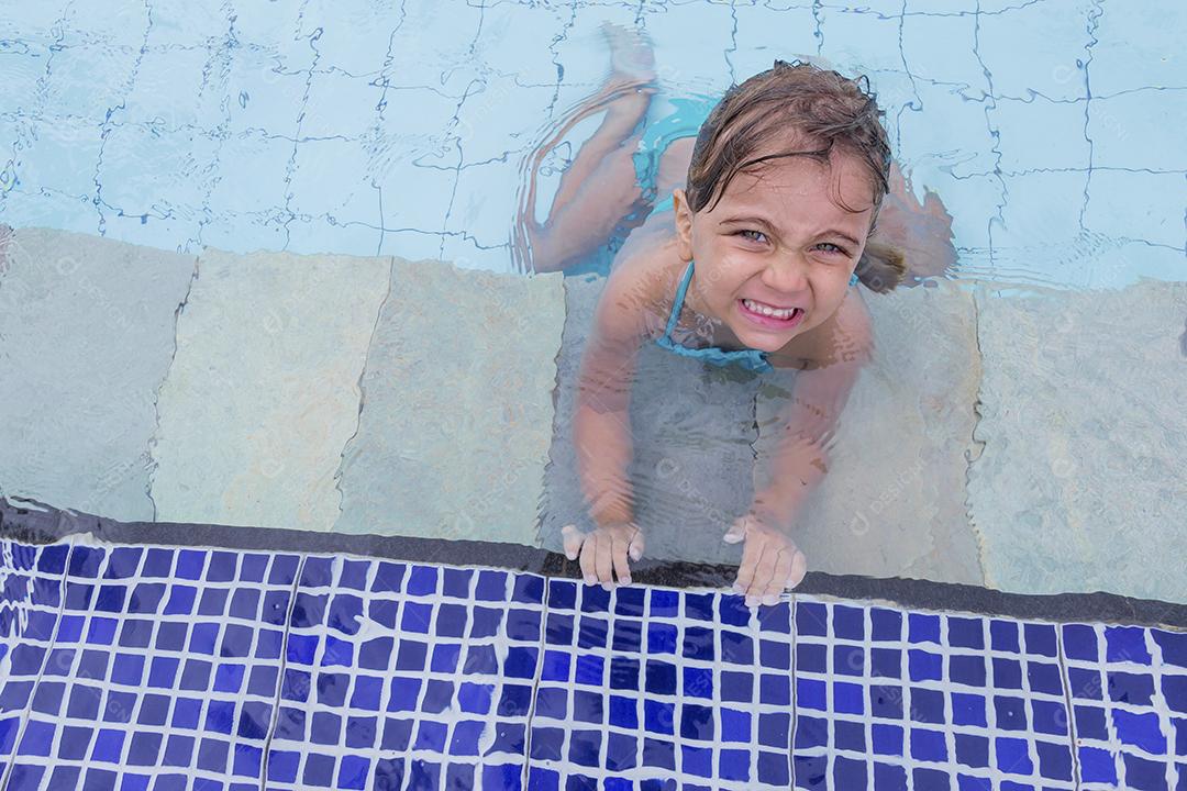 Garota feliz jogando na piscina no hotel de férias