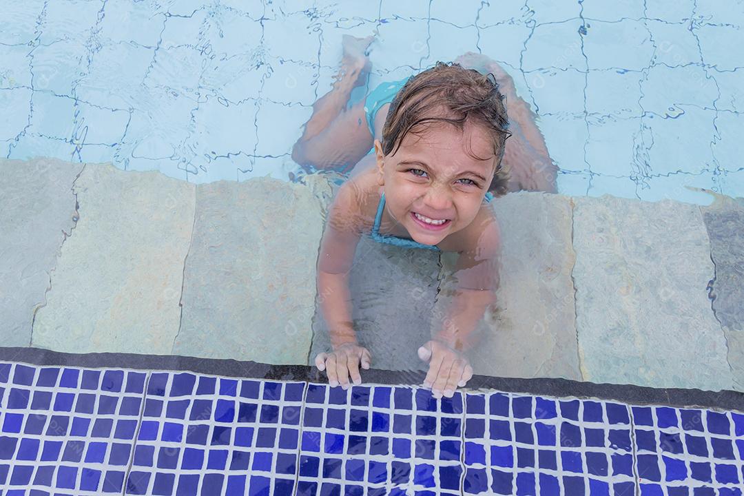 Garota feliz jogando na piscina no hotel de férias