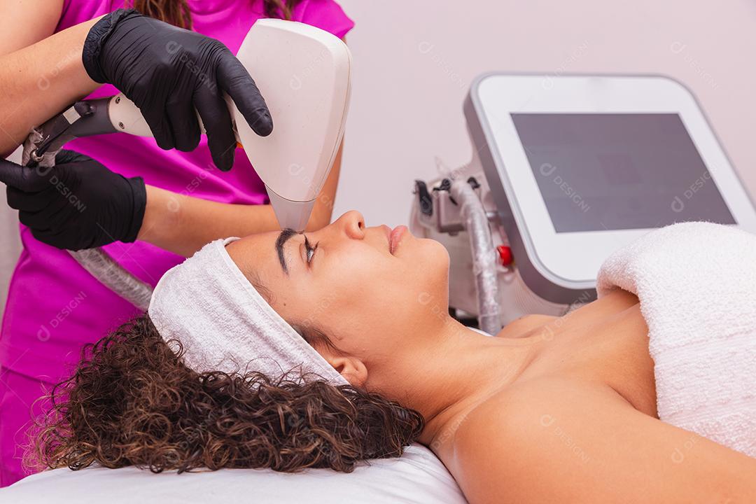 Mulher negra brasileira realizando depilação a laser na sobrancelha