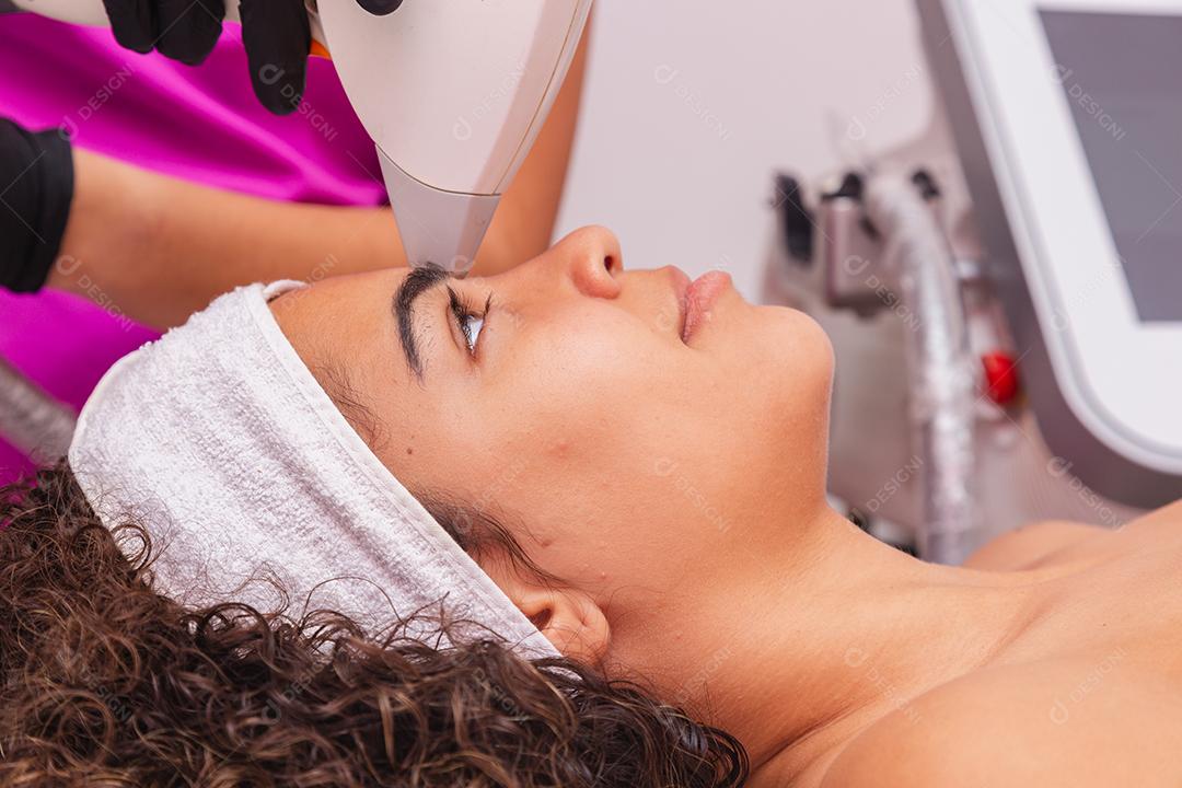 Mulher negra brasileira realizando depilação a laser na sobrancelha