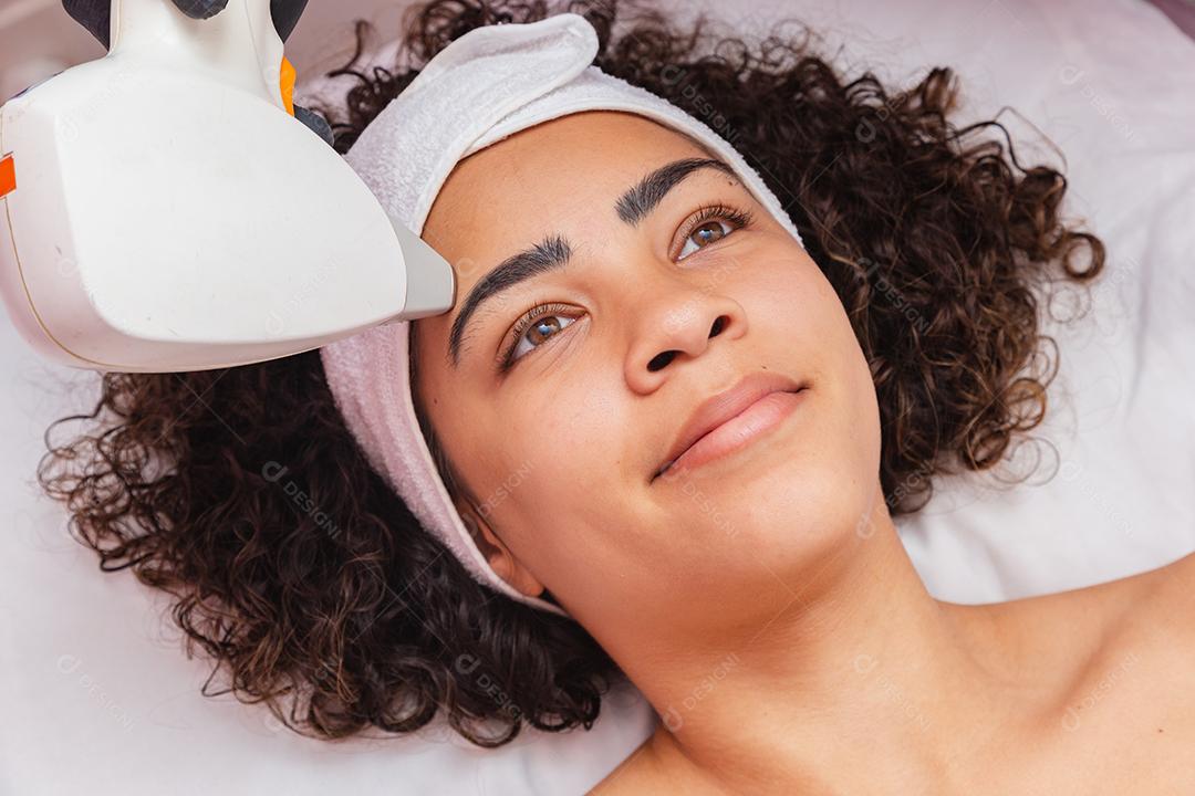 Mulher negra brasileira realizando depilação a laser na sobrancelha