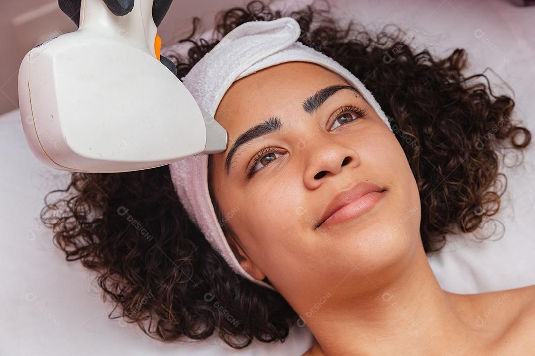 Mulher negra brasileira realizando depilação a laser na sobrancelha
