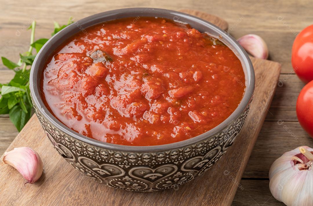 Molho de tomate, tomate, alho e ervas sobre a mesa de madeira.