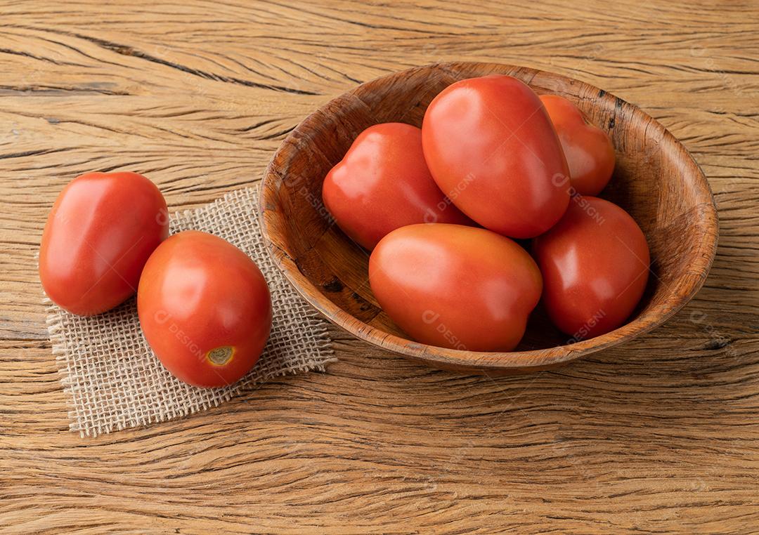 Tomates italianos em uma tigela sobre a mesa de madeira.