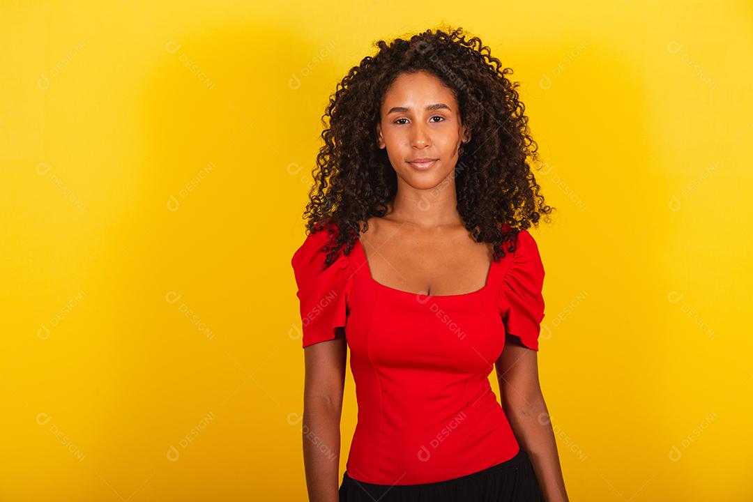 retrato de mulher morena de raça mista com grande cabelo afro, cabelo encaracolado em fundo amarelo.
