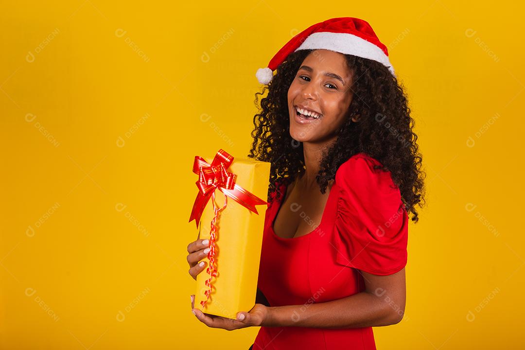 Jovem afro segurando um presente de Natal expressivo.