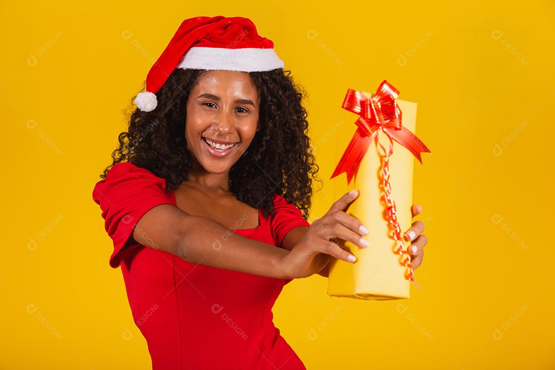 Jovem afro segurando um presente de Natal expressivo.