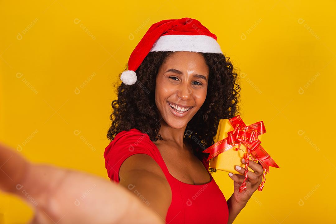 Mulher com chapéu de Papai Noel e tirar selfie com caixa de presente
