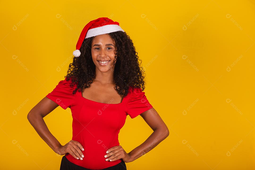 Linda garota afro segurando um presente de natal.Sorridente jovem afro-americana com chapéu de Natal