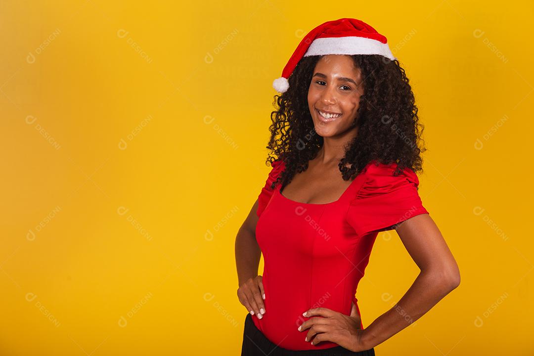 Linda garota afro segurando um presente de natal.Sorridente jovem afro-americana com chapéu de Natal