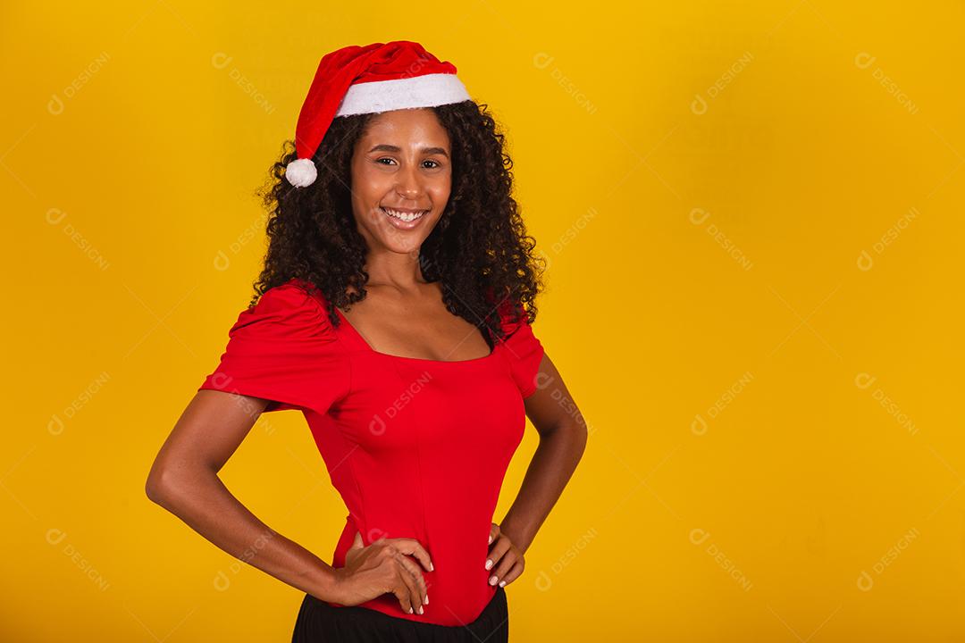Linda garota afro segurando um presente de natal.Sorridente jovem afro-americana com chapéu de Natal