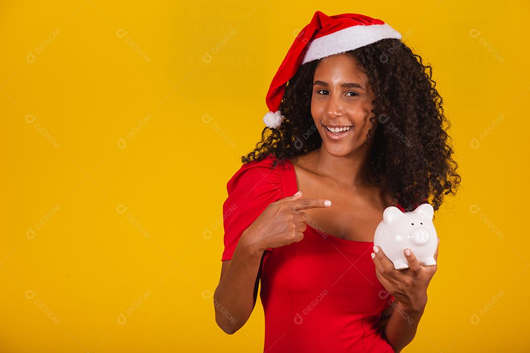 Mulher jovem e bonita pegando as economias de um cofrinho para comprar os presentes de natal