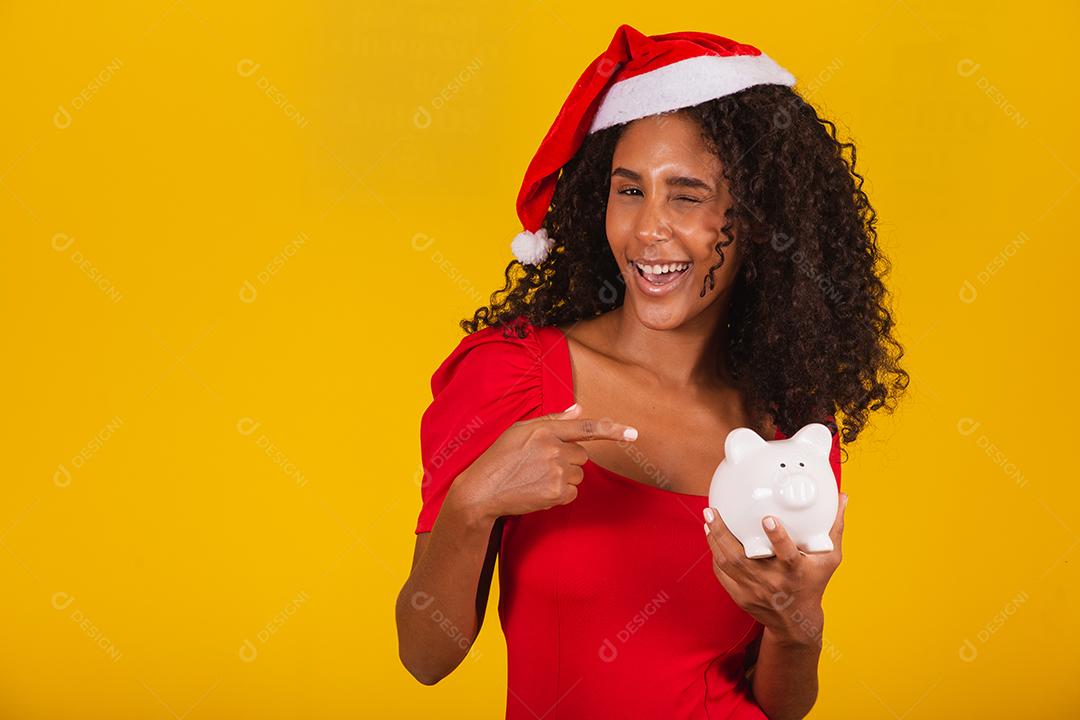 Mulher jovem e bonita pegando as economias de um cofrinho para comprar os presentes de natal