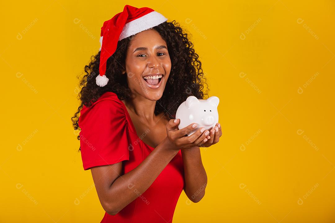 Mulher jovem e bonita pegando as economias de um cofrinho para comprar os presentes de natal