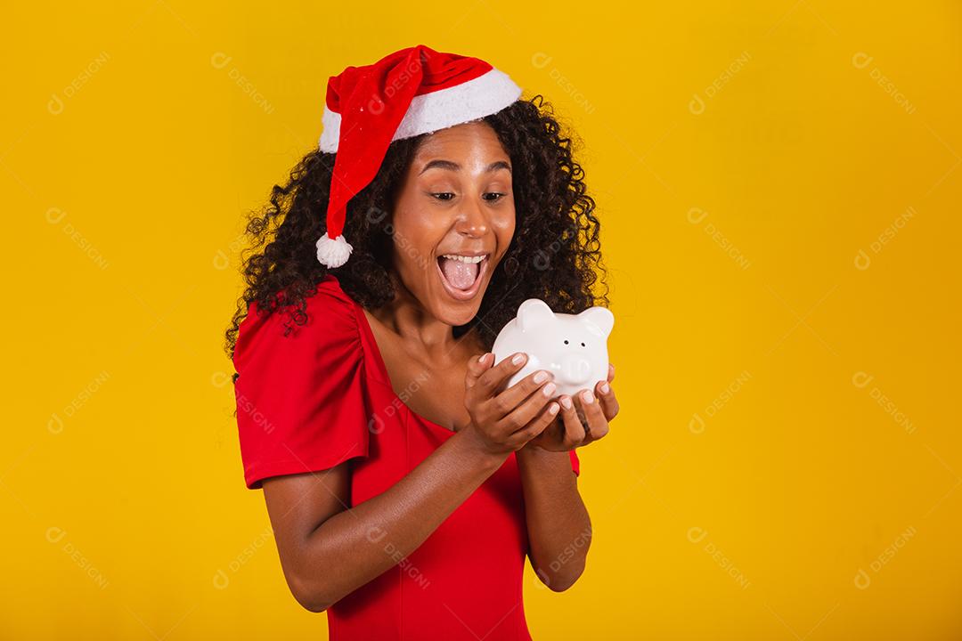 Mulher jovem e bonita pegando as economias de um cofrinho para comprar os presentes de natal