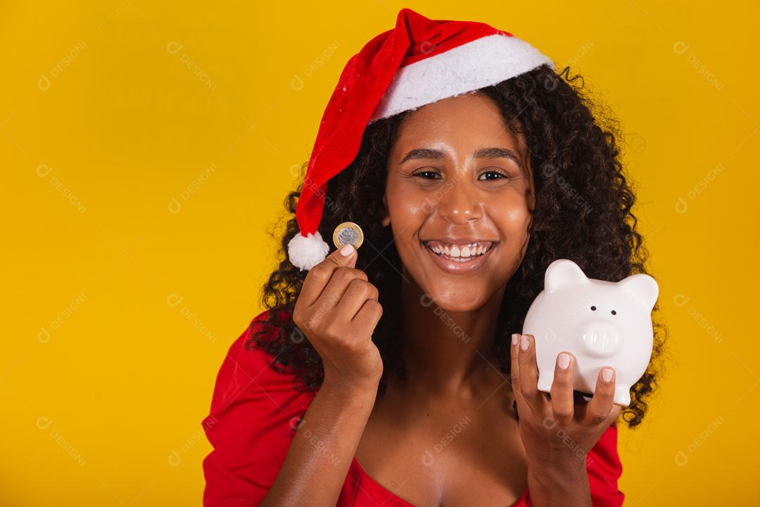 Mulher jovem e bonita pegando as economias de um cofrinho para comprar os presentes de natal