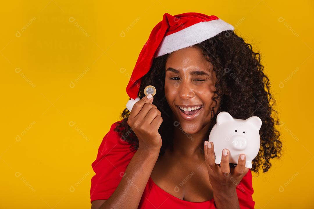 Mulher jovem e bonita pegando as economias de um cofrinho para comprar os presentes de natal