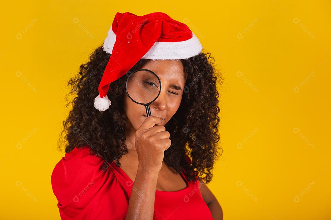 Linda garota afro segurando um presente de natal.Sorridente jovem afro-americana com chapéu de Natal