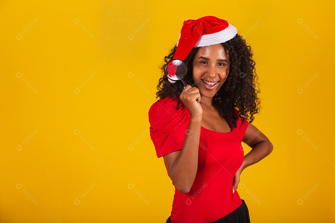 Linda garota afro segurando um presente de natal.Sorridente jovem afro-americana com chapéu de Natal