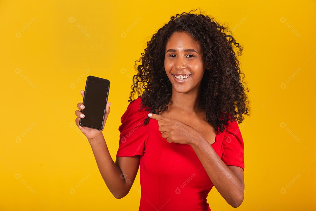 Sorrindo jovem Santa no chapéu de Natal segurando o celular com tela em branco vazia isolada em fundo amarelo.