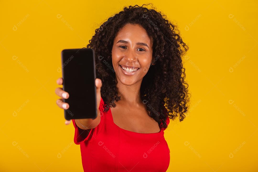 Sorrindo jovem Santa no chapéu de Natal segurando o celular com tela em branco vazia isolada em fundo amarelo.