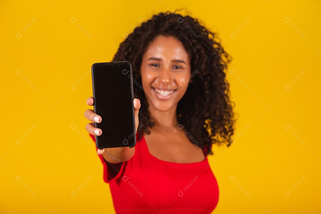 Sorrindo jovem Santa no chapéu de Natal segurando o celular com tela em branco vazia isolada em fundo amarelo.