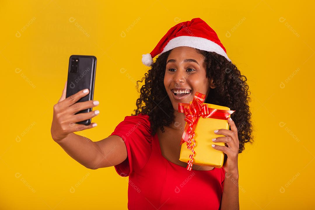 Mulher com chapéu de Papai Noel e tirar selfie com caixa de presente