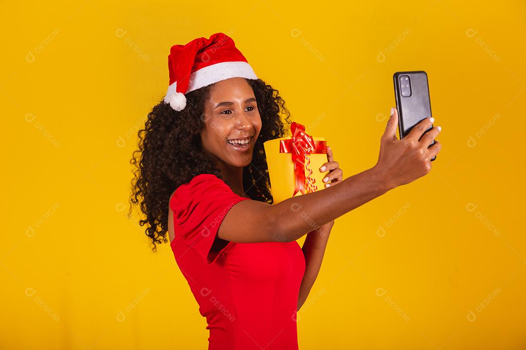 Mulher com chapéu de Papai Noel e tirar selfie com caixa de presente