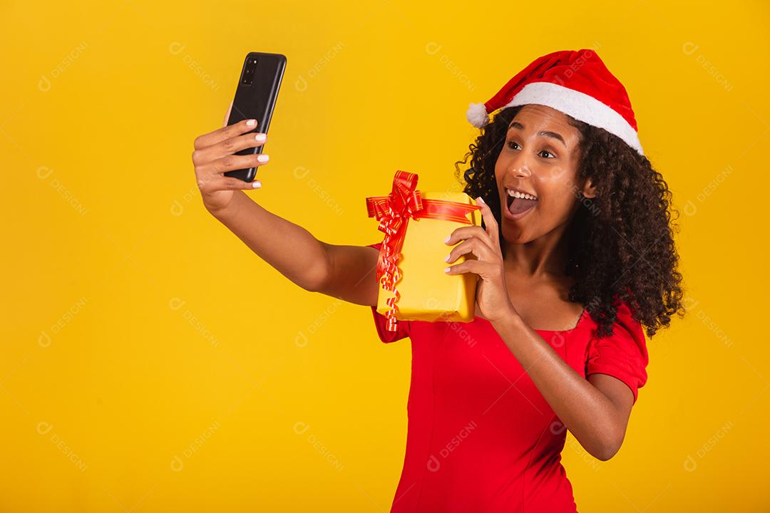 Mulher com chapéu de Papai Noel e tirar selfie com caixa de presente
