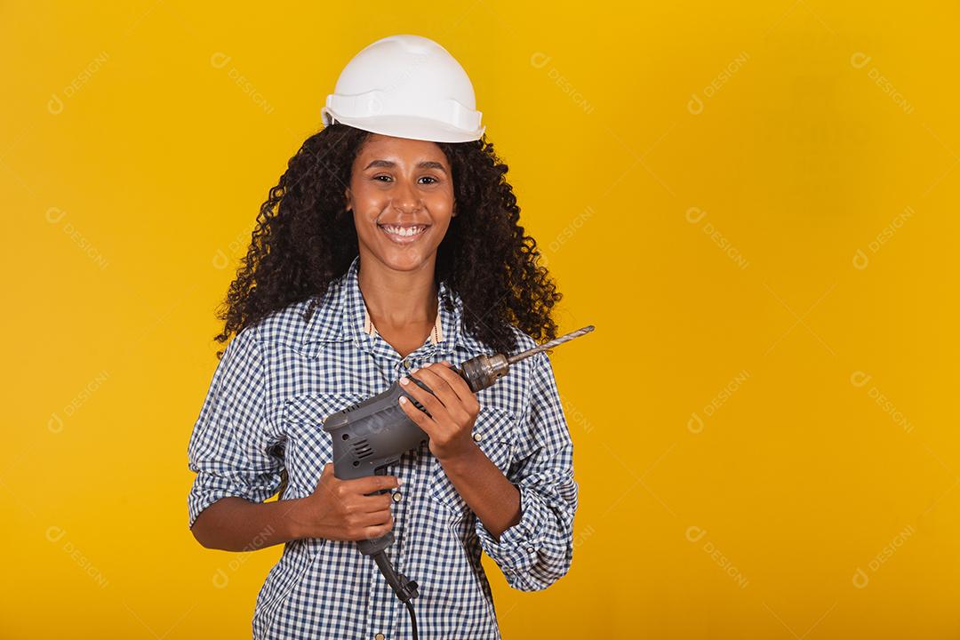 Mulher empreiteira com uma broca em fundo amarelo.