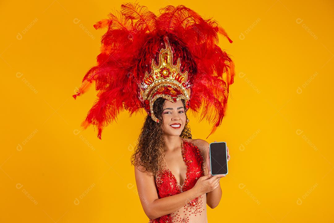 Mulher jovem e bonita em traje especial de penas de carnaval segurando um smartphone com tela em branco