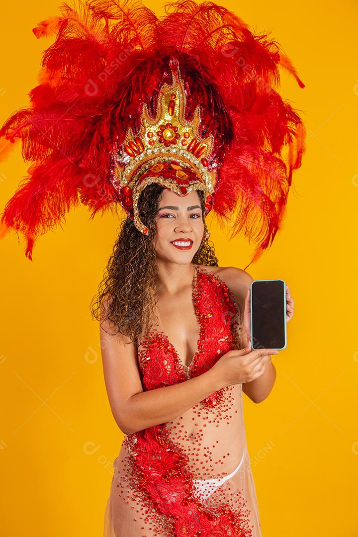 Mulher jovem e bonita em traje especial de penas de carnaval segurando um smartphone com tela em branco
