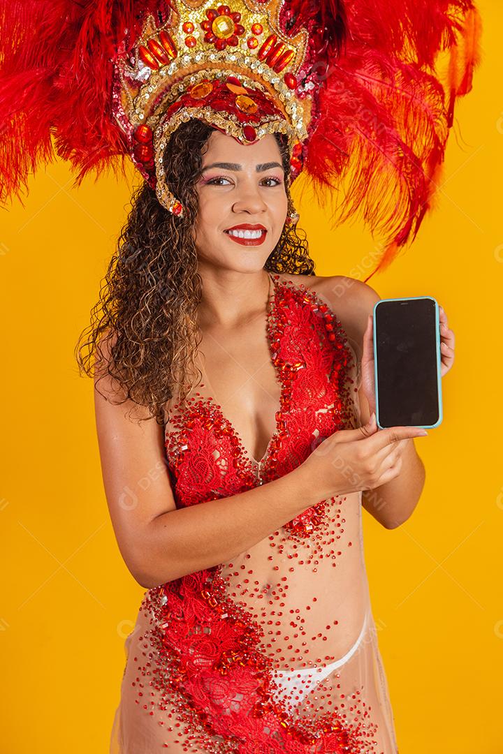 Mulher jovem e bonita em traje especial de penas de carnaval segurando um smartphone com tela em branco