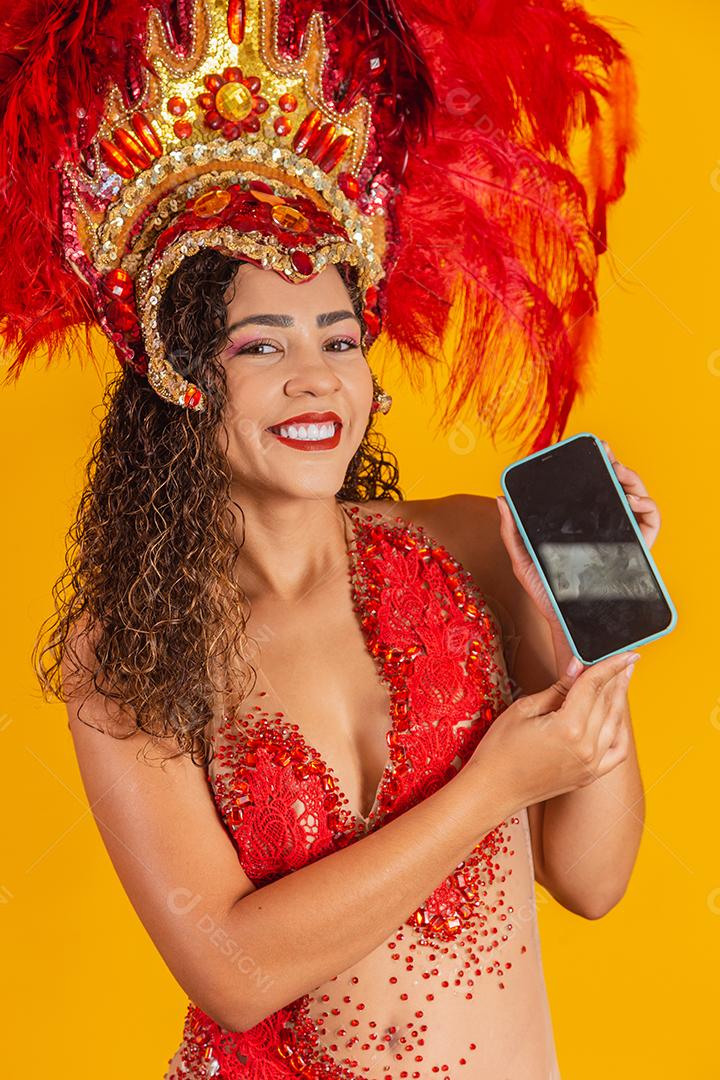 Mulher jovem e bonita em traje especial de penas de carnaval segurando um smartphone com tela em branco