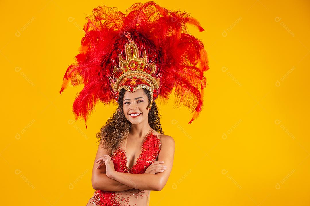 Linda dançarina está de pé cruza as mãos. Ela está vestindo traje de penas vermelhas.