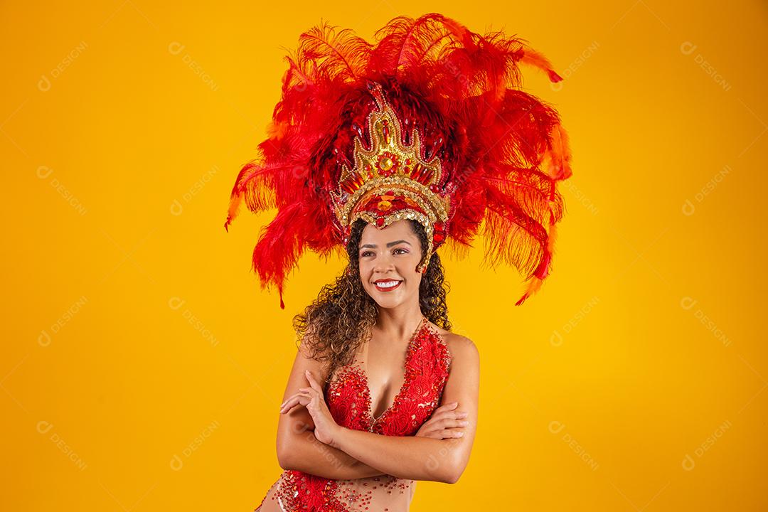 Linda dançarina está de pé cruza as mãos. Ela está vestindo traje de penas vermelhas.