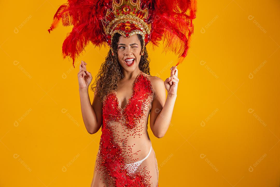 Retrato de mulher afro brasileira com roupa de carnaval com os dedos cruzados desejando sorte