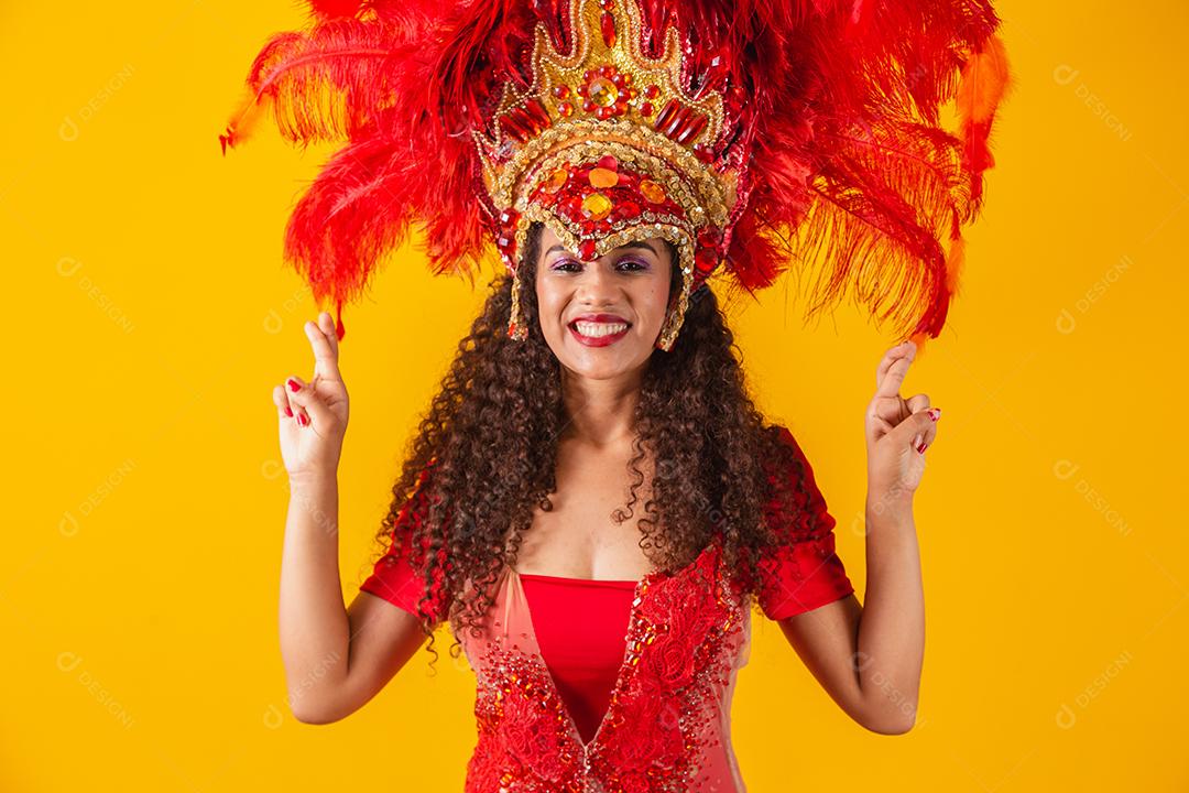 Retrato de mulher afro brasileira com roupa de carnaval com os dedos cruzados desejando sorte