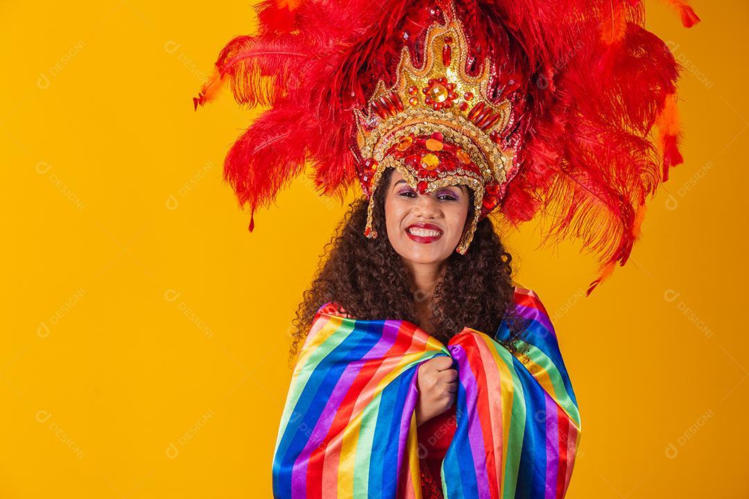 Linda mulher afro com roupa de carnaval de bandeira lgbt em fundo amarelo.
