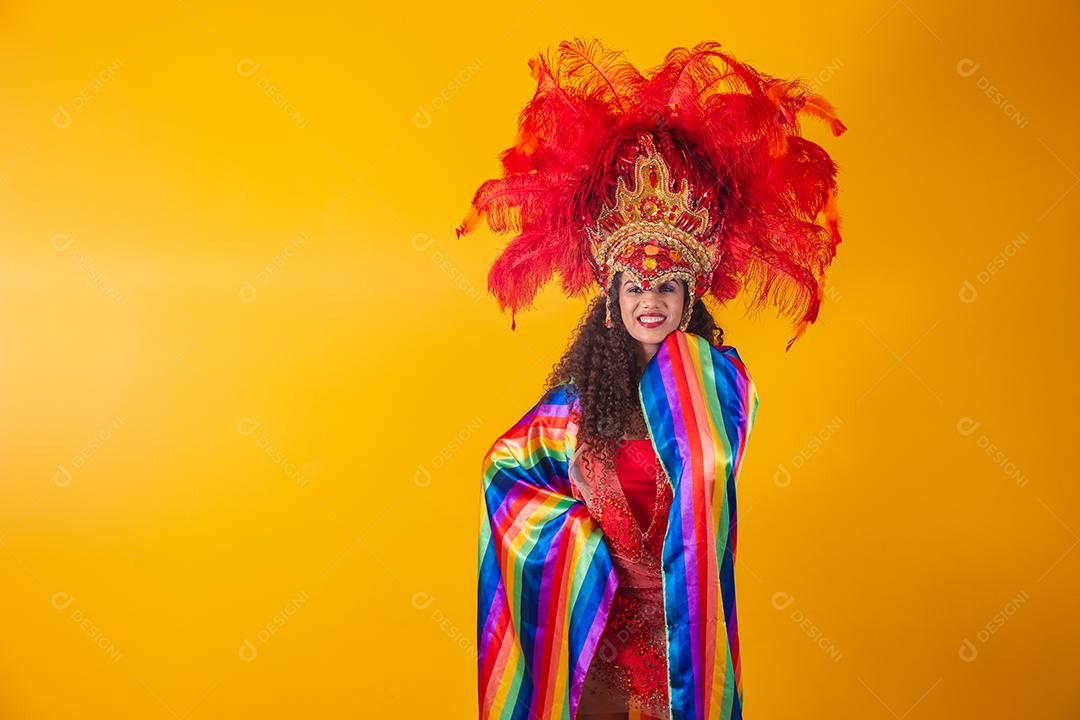 Linda mulher afro com roupa de carnaval de bandeira lgbt em fundo amarelo.